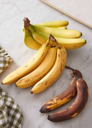 Three bundles of bananas, one slightly green, one spotty brown, and one super ripe.