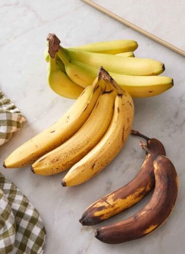 Three bundles of bananas, one slightly green, one spotty brown, and one super ripe.