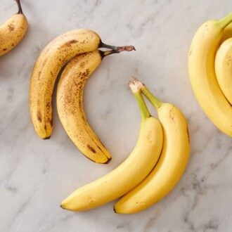 Multiple bundles of bananas on a marble surface.