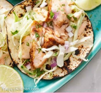 Pinterest graphic of a close up view of salmon tacos on a platter with some cut limes around.