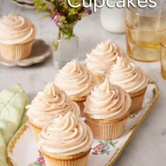 Pinterest graphic of a platter of six snickerdoodle cupcakes. Flowers, drink, milk, and a single snickerdoodle cupcake in the background.