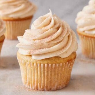 Multiple snickerdoodle cupcakes on a marble surface.