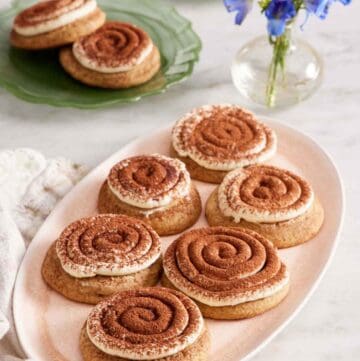 A platter of tiramisu cookies with a vase of flowers and two more plates of tiramisu cookies in the background.