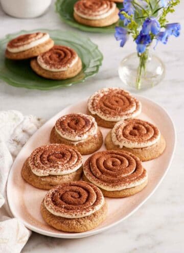 A platter of tiramisu cookies with a vase of flowers and two more plates of tiramisu cookies in the background.