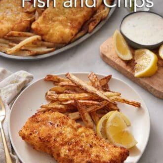 Pinterest graphic of a plate of air fryer fish and chips with lemon wedges. A platter with more in the background also with some lemon wedges and tartar sauce on the side.