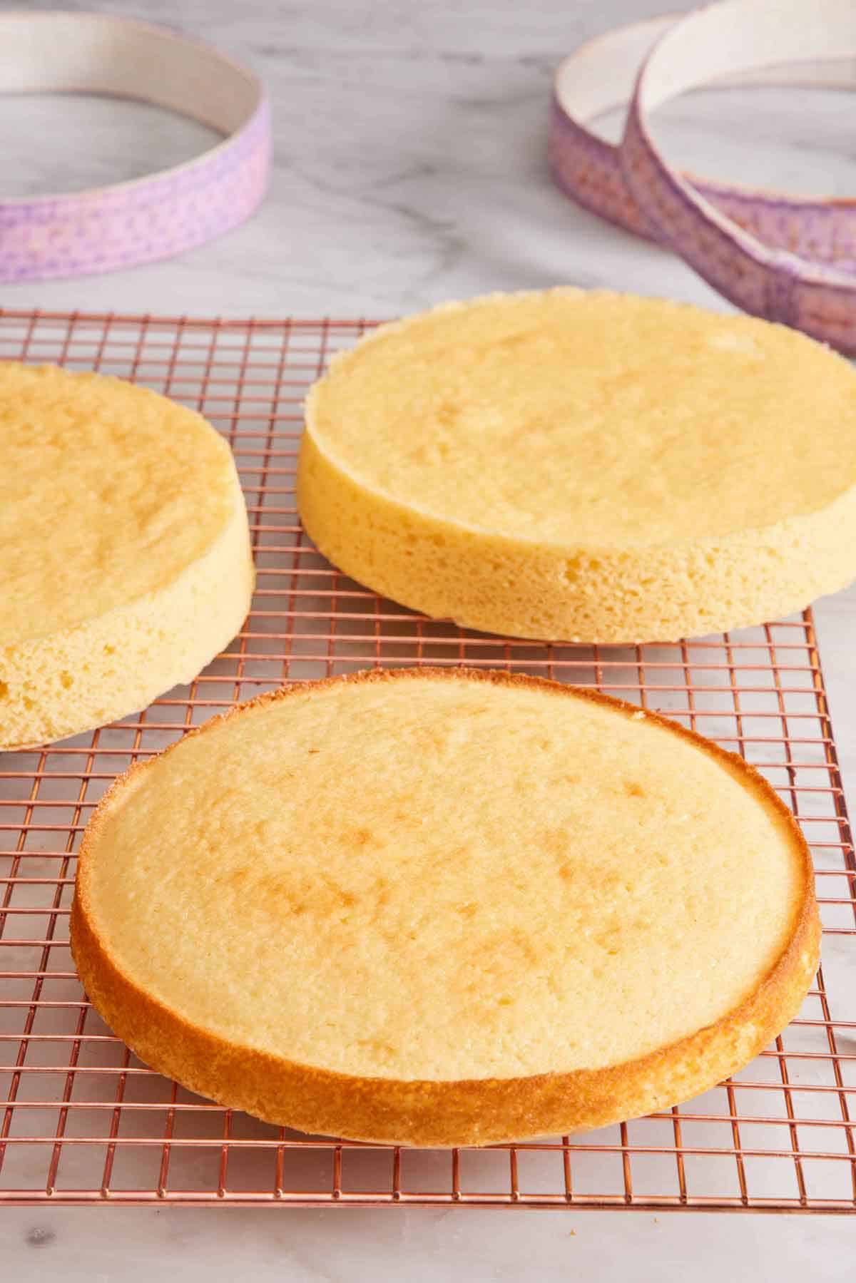 Three cake layers on a cooling rack. Fabric cake strips in the background.