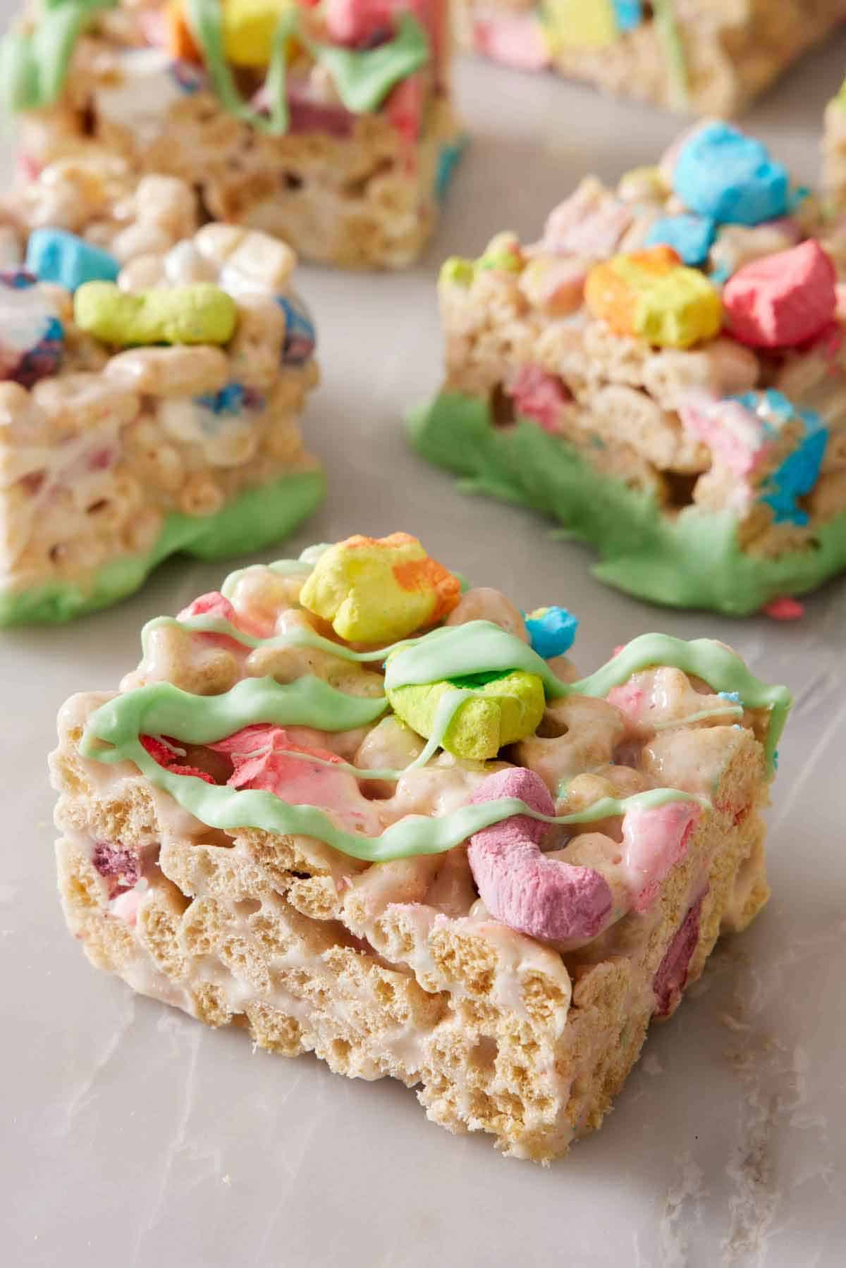 Lucky Charms treats on a marble surface with green colored chocolate drizzle.