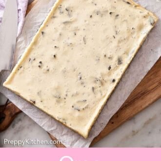 Pinterest graphic of an uncut slab of Oreo cheesecake bars on a parchment-lined wooden serving board.