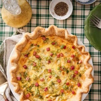 Pinterest graphic of a quiche with ham and green onions. A bowl of salt, pepper, salad dressing, and salad on the side.