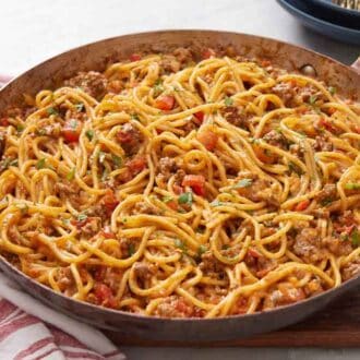 A skillet of taco spaghetti topped with chopped cilantro.