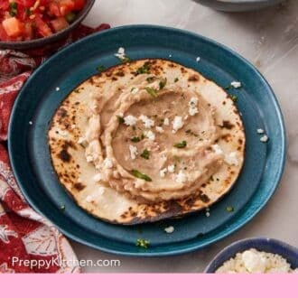 Pinterest graphic showing mashed beans on a toasted tortilla on a blue plate.