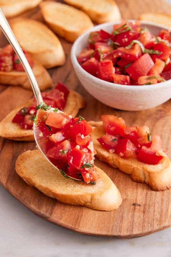 Bruschetta assembled with tomato topping spooned onto toasted bread.