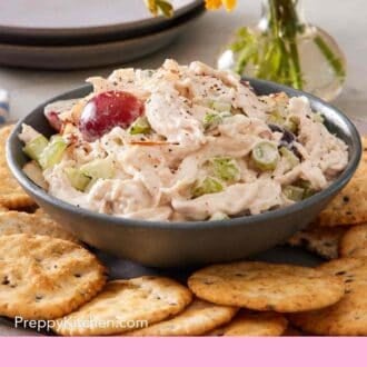 Pinterest graphic showing chicken salad and crackers with flowers in the background.