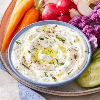 Easy tzatziki in a bowl on a platter with vegetables.