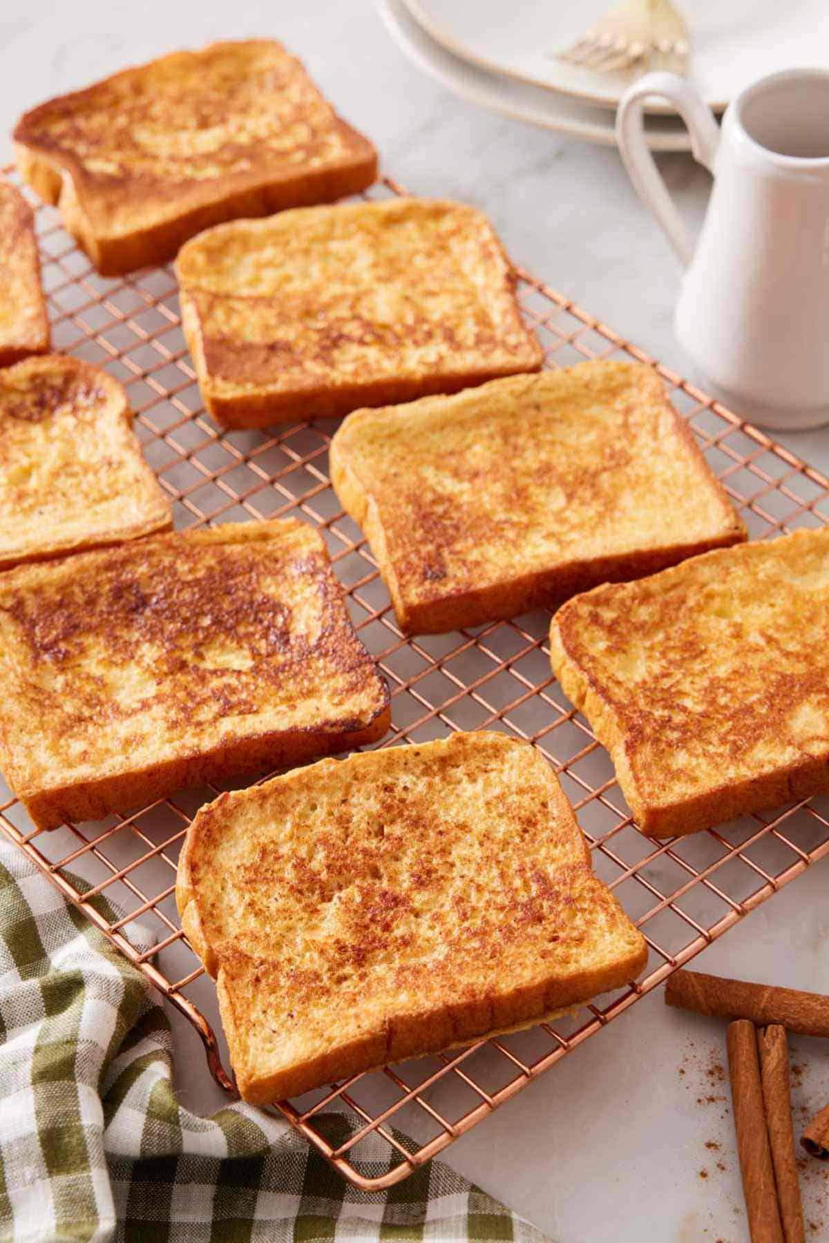 Several slices of homemade French toast in a single layer on a wire rack.
