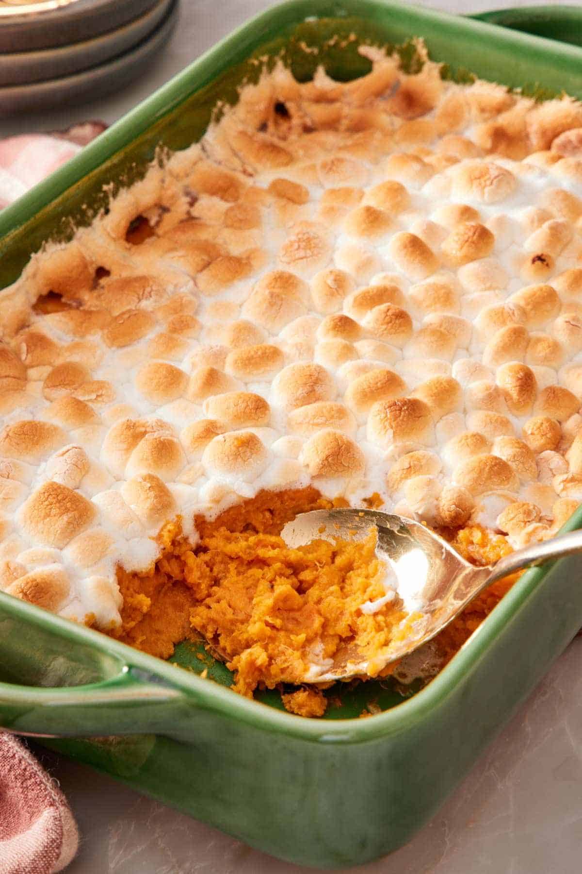 Sweet potato casserole with a golden marshmallow topping with a spoonful taken out.