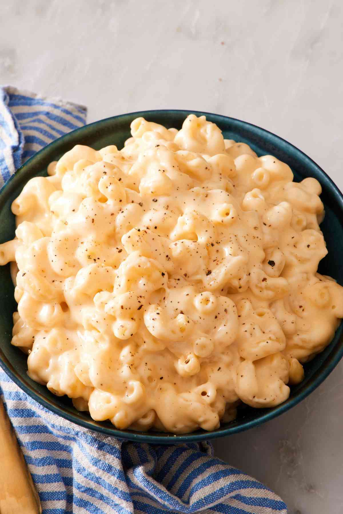 Close-up of macaroni and cheese in a green bowl with black pepper sprinkled on top.