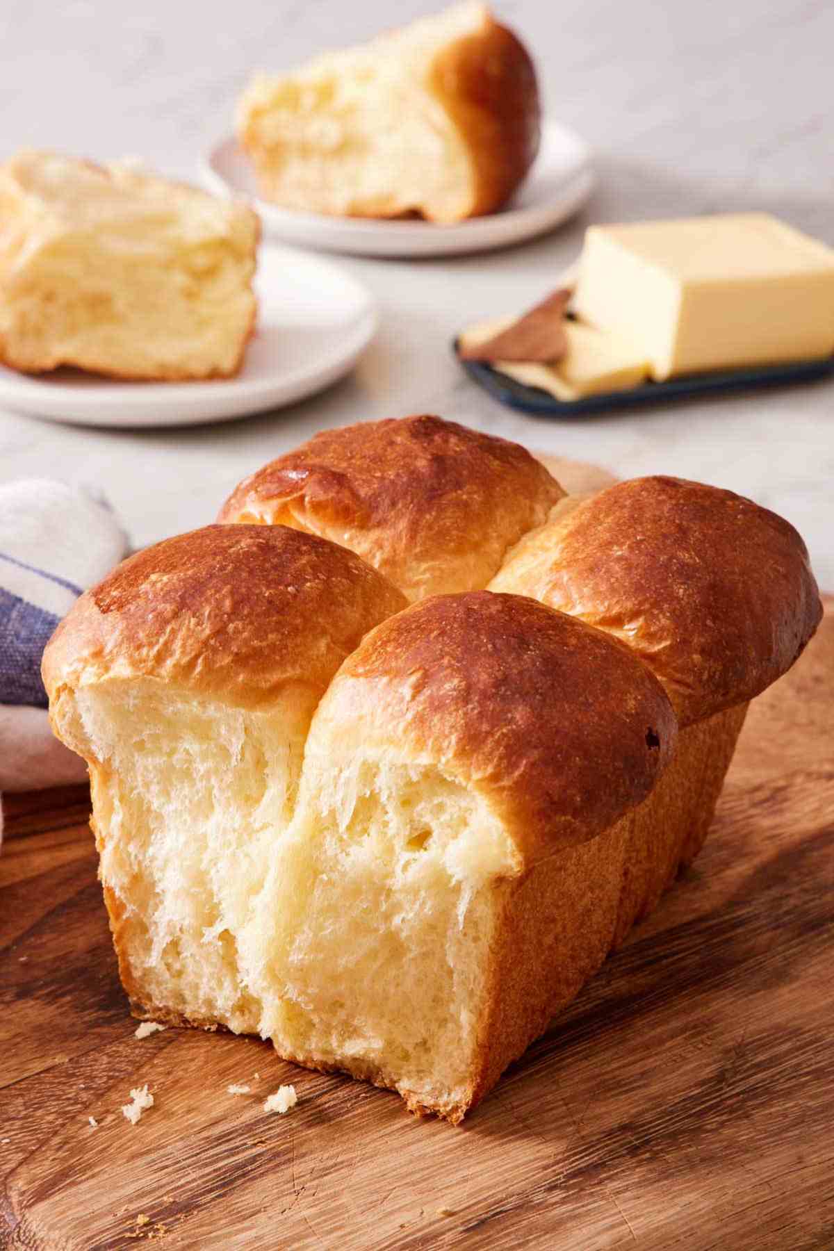 Nantaise brioche bread with rolls torn off on a wooden cutting board.