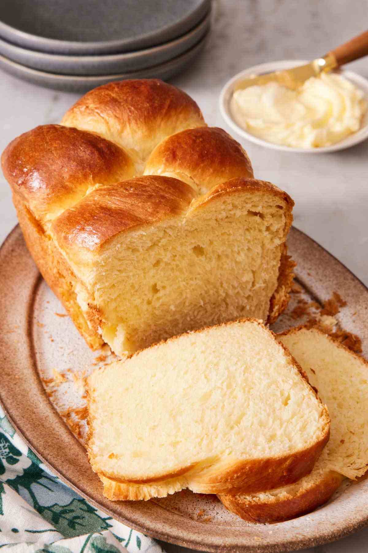 Braided brioche loaf with half of it sliced.