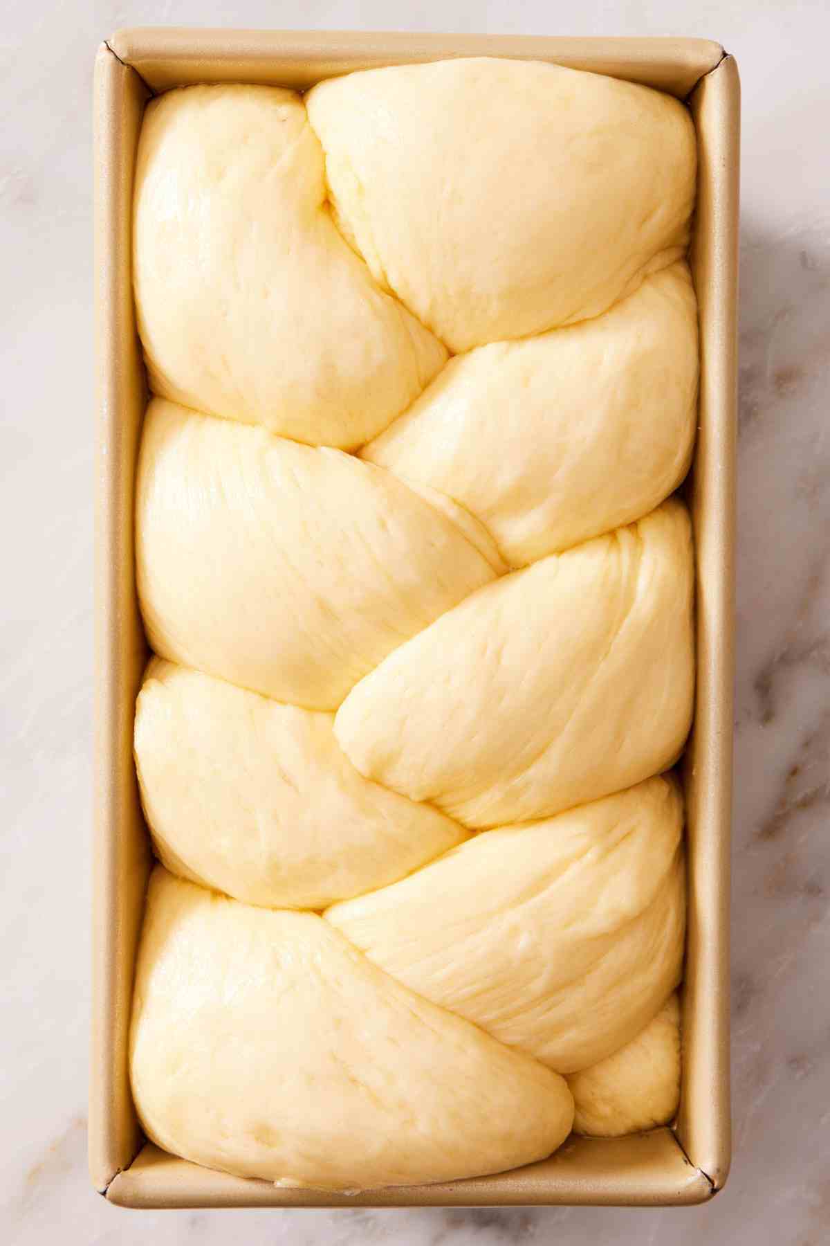 Brioche dough in a loaf pan after proofing.
