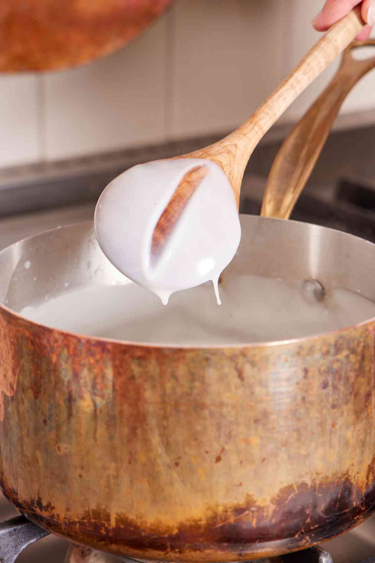 Spoon test image for the milk and cornstarch mixture showing how it coats the back of a spoon and leaves a clean line when you swipe a finger through it.
