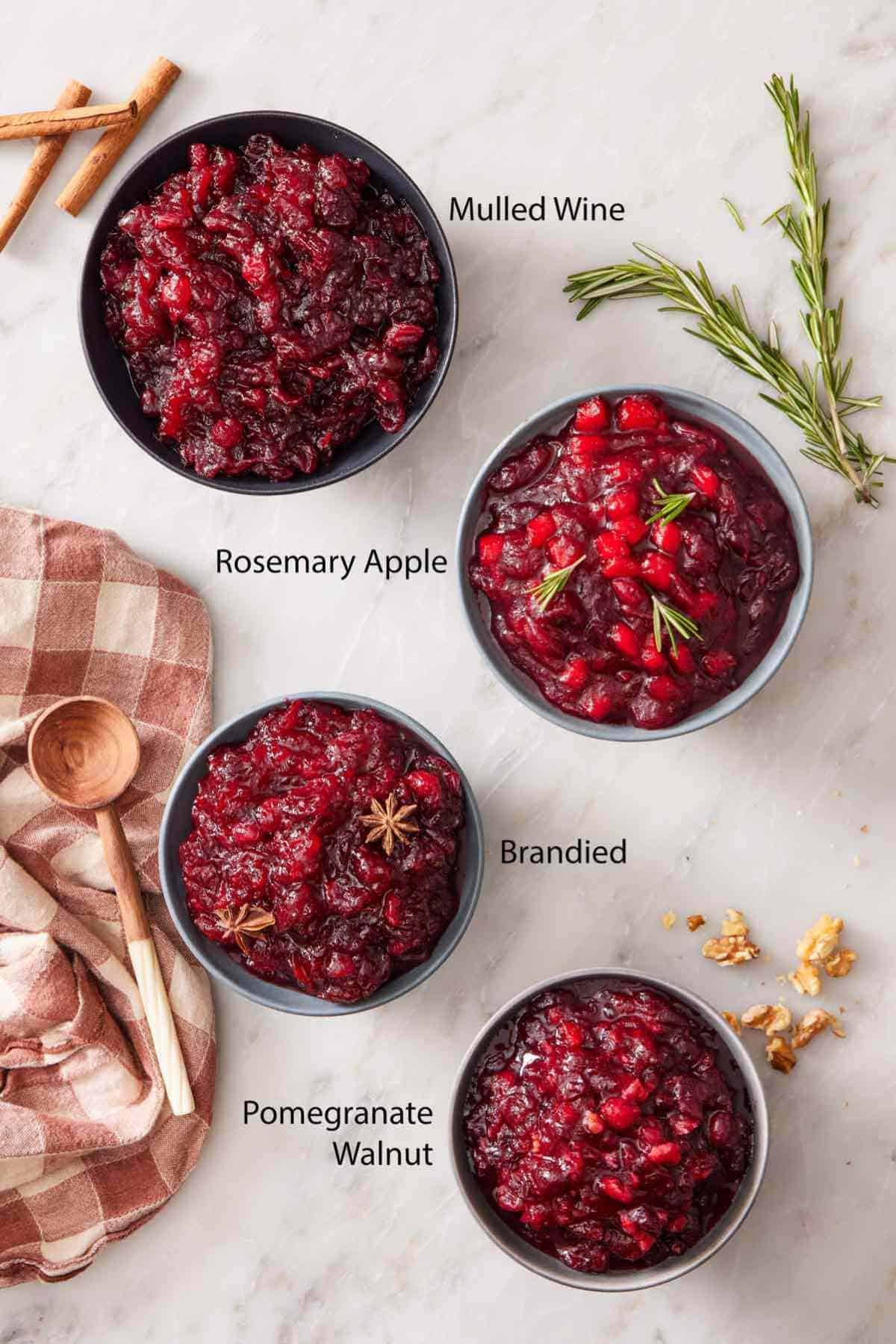 Overhead shot of four bowls of cranberry sauce, each with different flavor combinations.