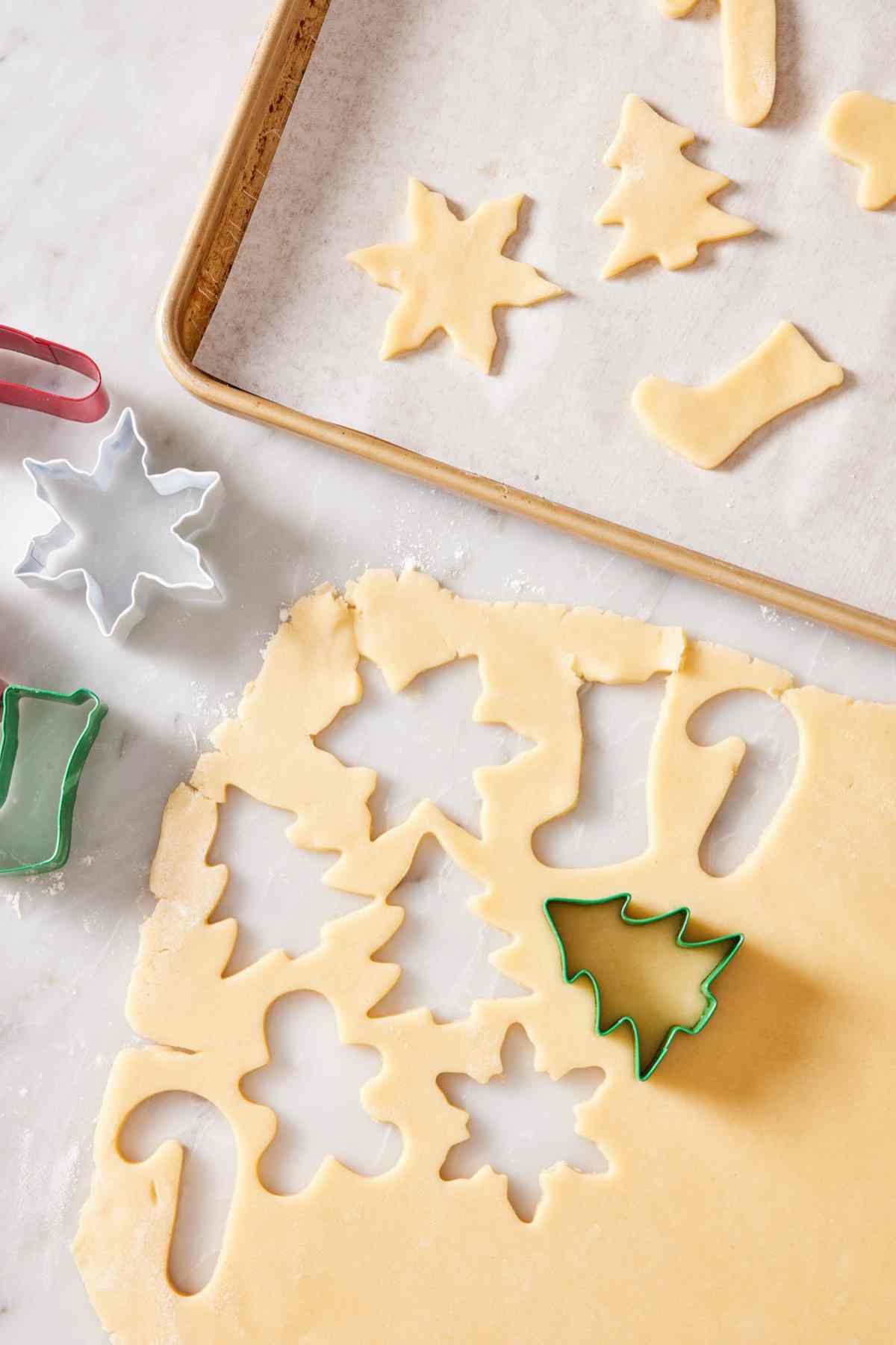 Overhead view of sugar cookie dough cut into festive Christmas shapes.