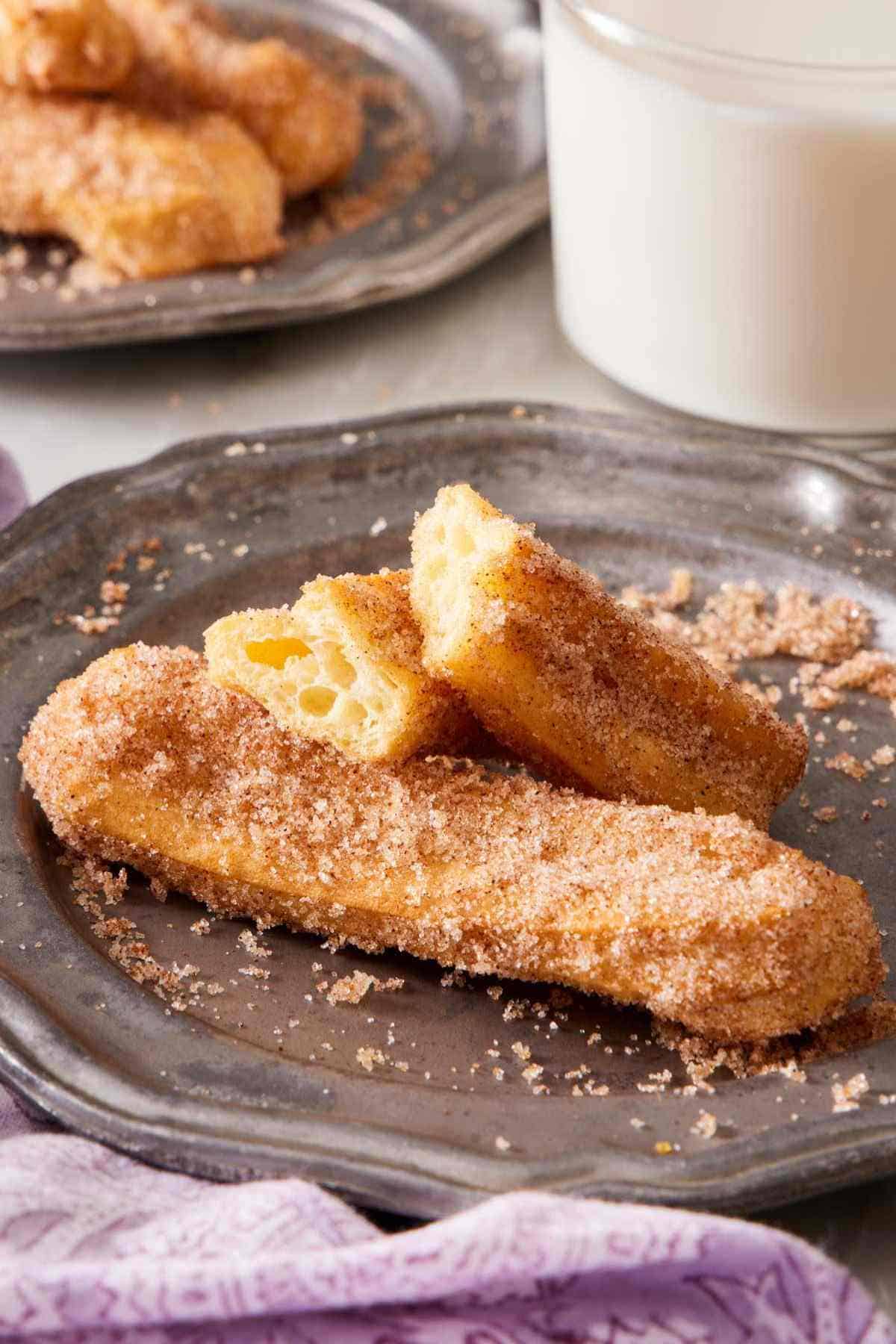 Two air fryer churros on a plate, one torn in two to show the texture inside.