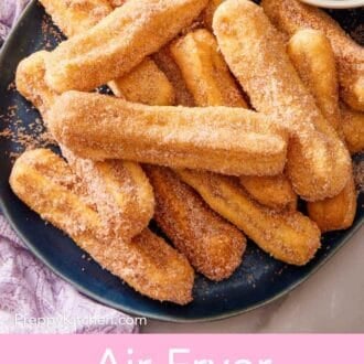 Pinterest graphic showing several air fryer churros on a blue platter with a small bowl of dipping sauce.