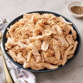 Instant Pot shredded chicken in a bowl on a marble countertop.