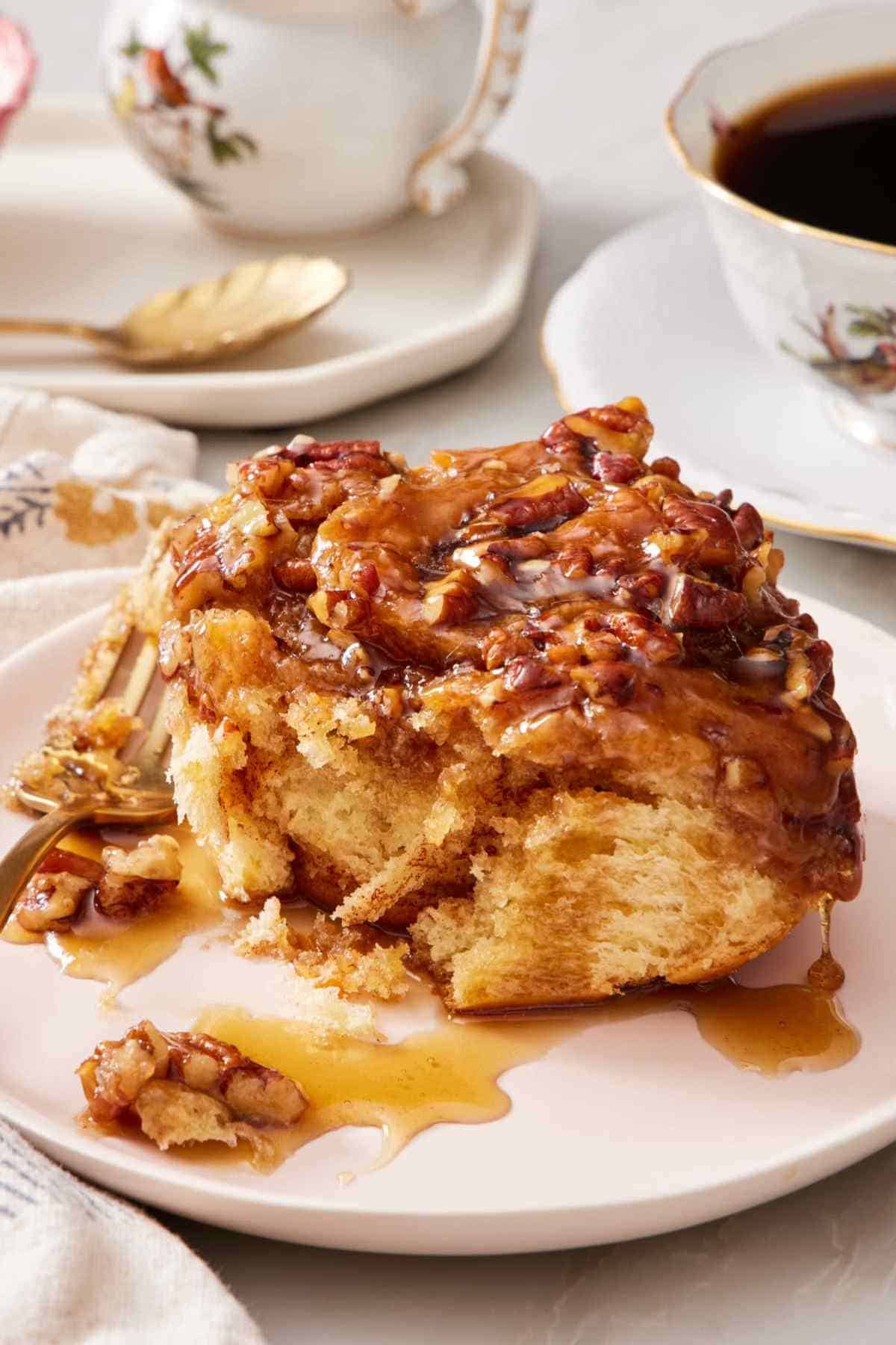 Close-up of a sticky bun on a plate with a fork.