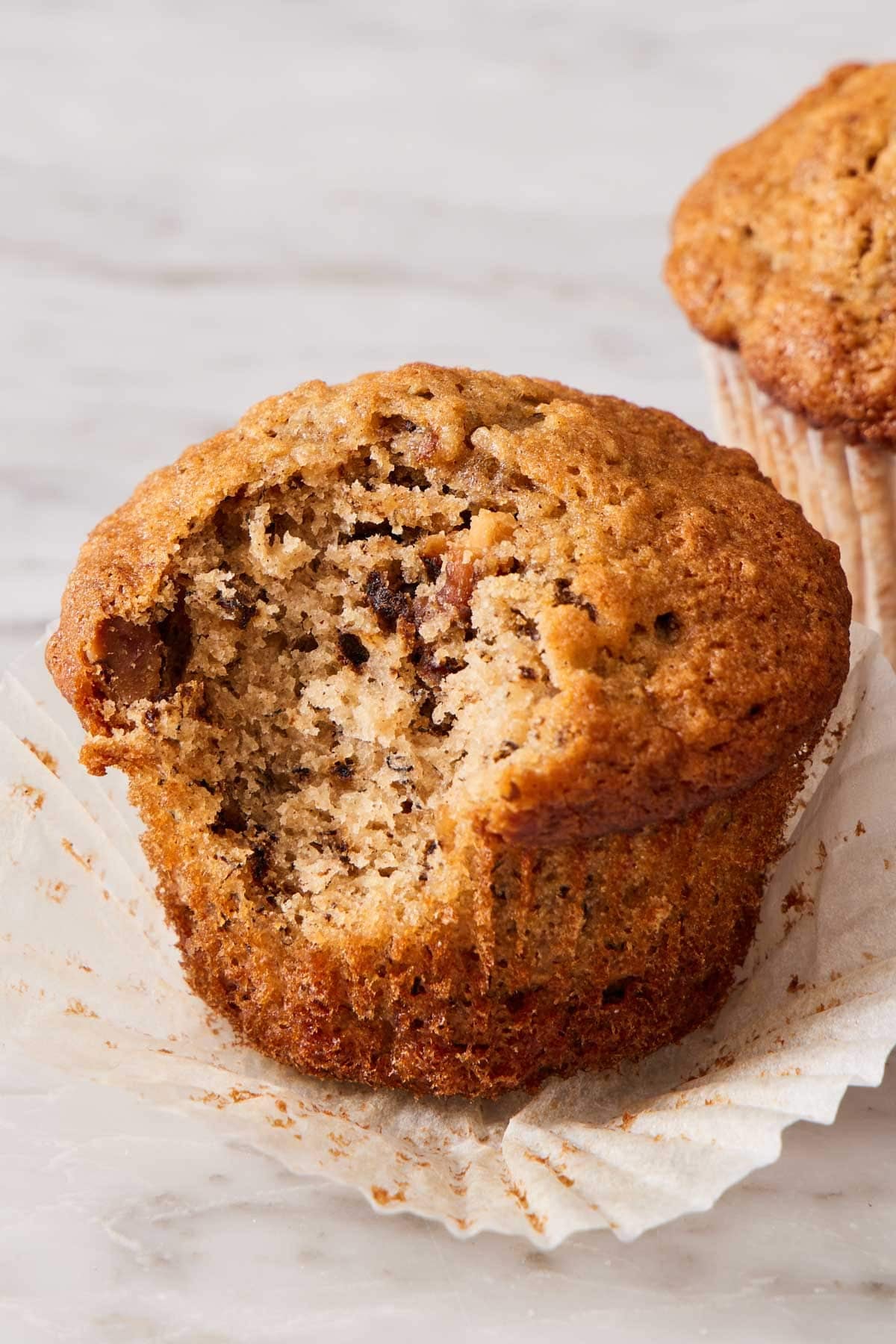 A banana muffin on a marble countertop with a bite taken out.