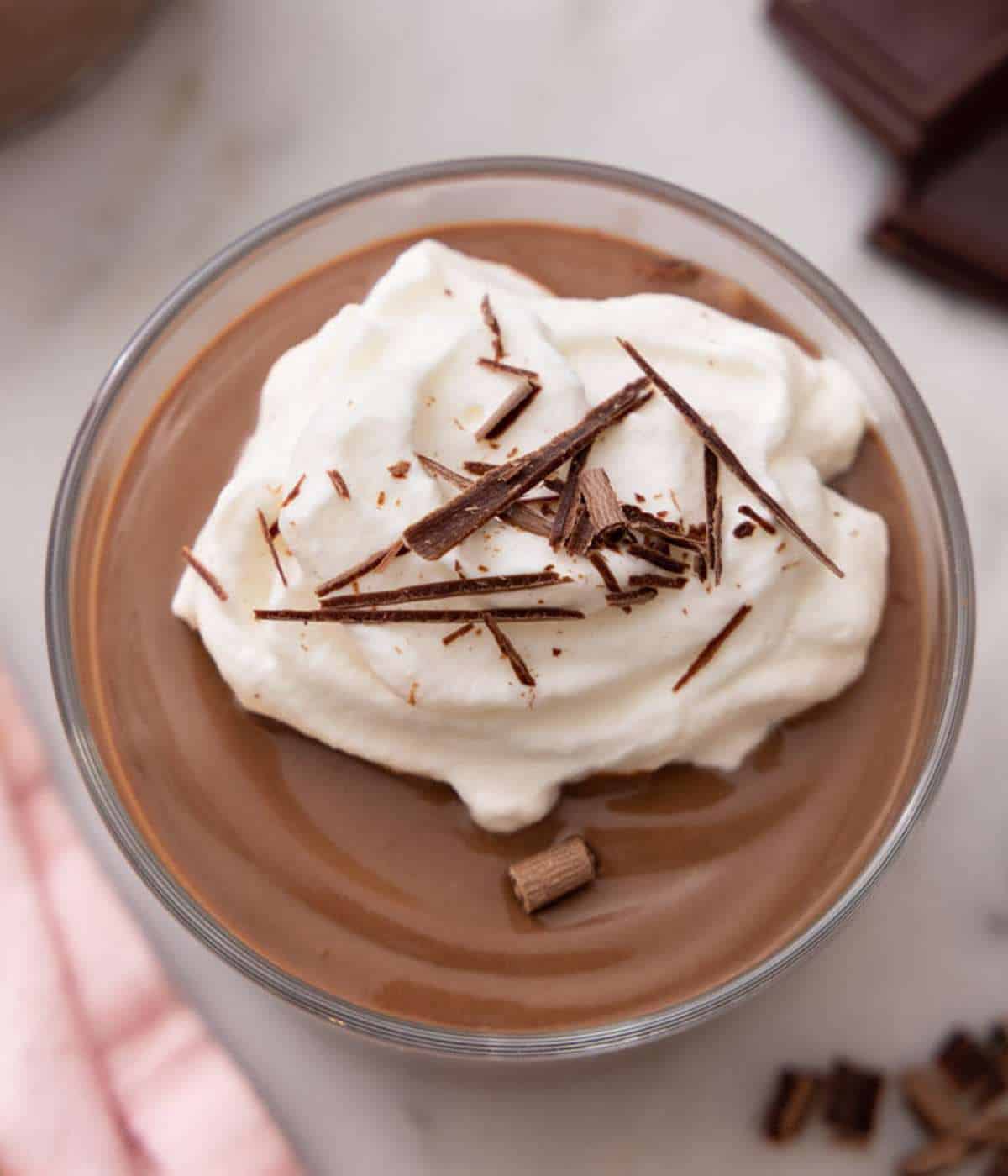 Overhead shot of homemade chocolate pudding topped with whipped cream and chocolate shavings.