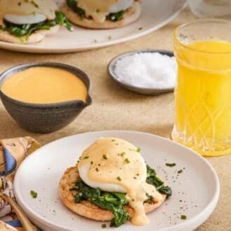Pinterest graphic showing eggs Florentine on a plate with a glass of orange juice and hollandaise sauce to the side.