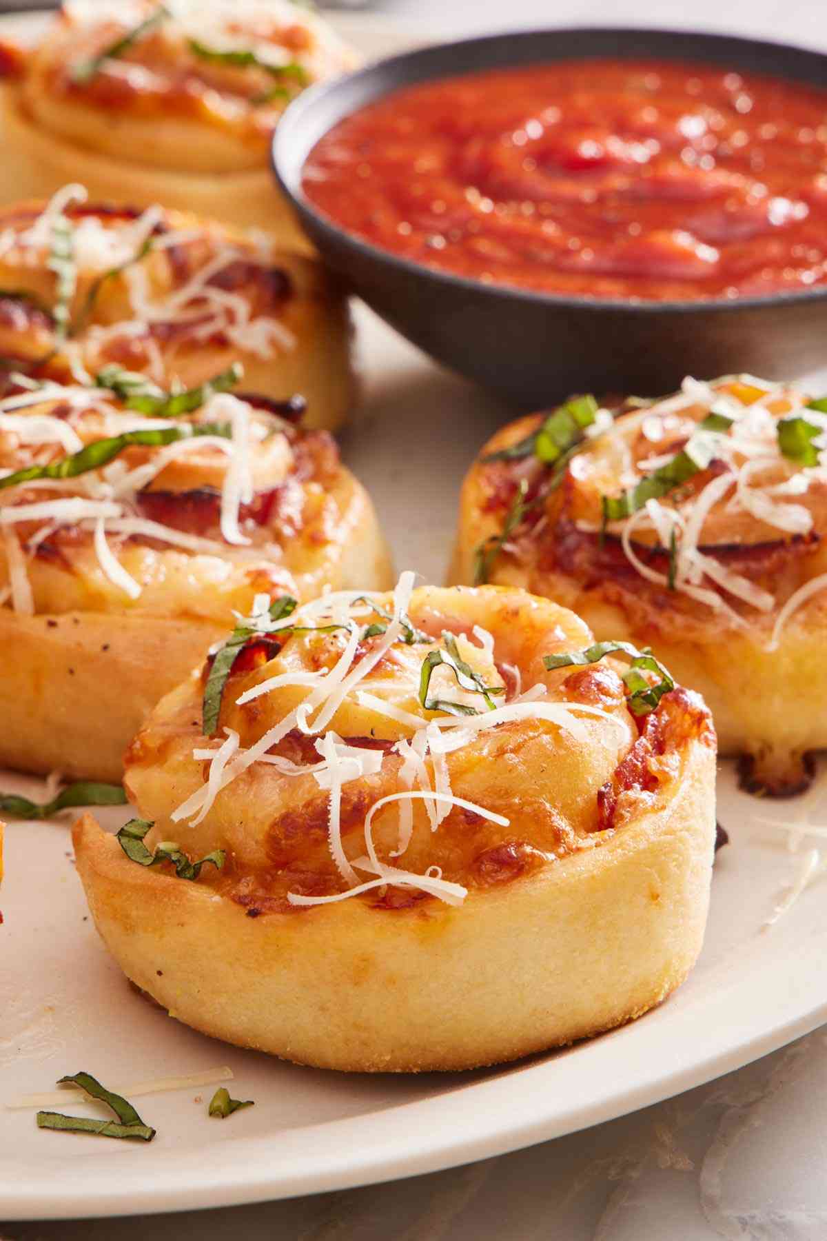 Close-up of pizza rolls on a platter with pizza sauce in the background.