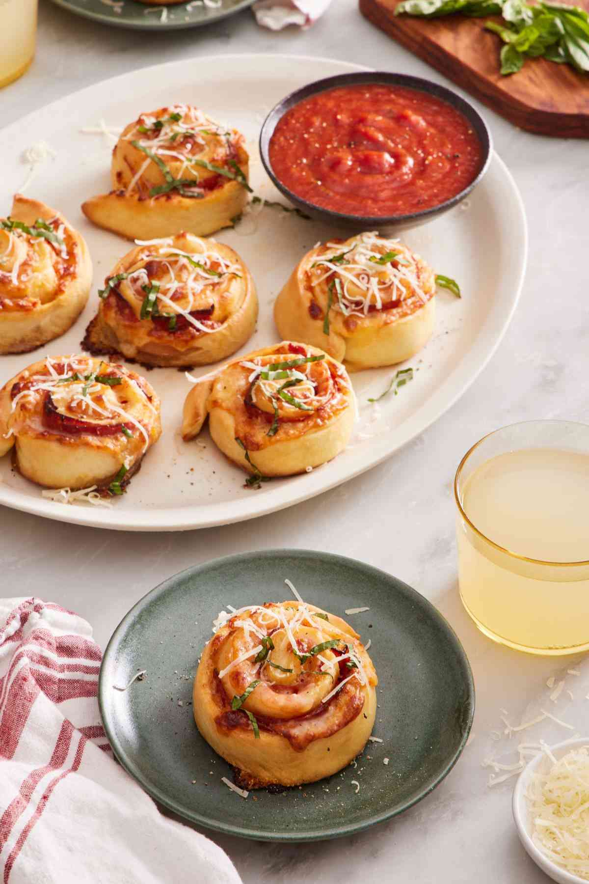 Overhead shot of a pizza roll on a plate with more on a platter off to the side.