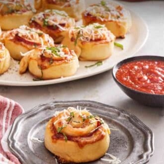 Pinterest graphic showing a single pizza roll on a plate with a bowl of sauce. There's a platter with more pizza rolls in the background.