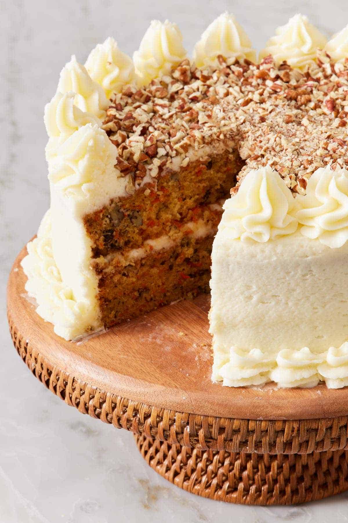 Carrot cake on a cake stand with a slice removed.