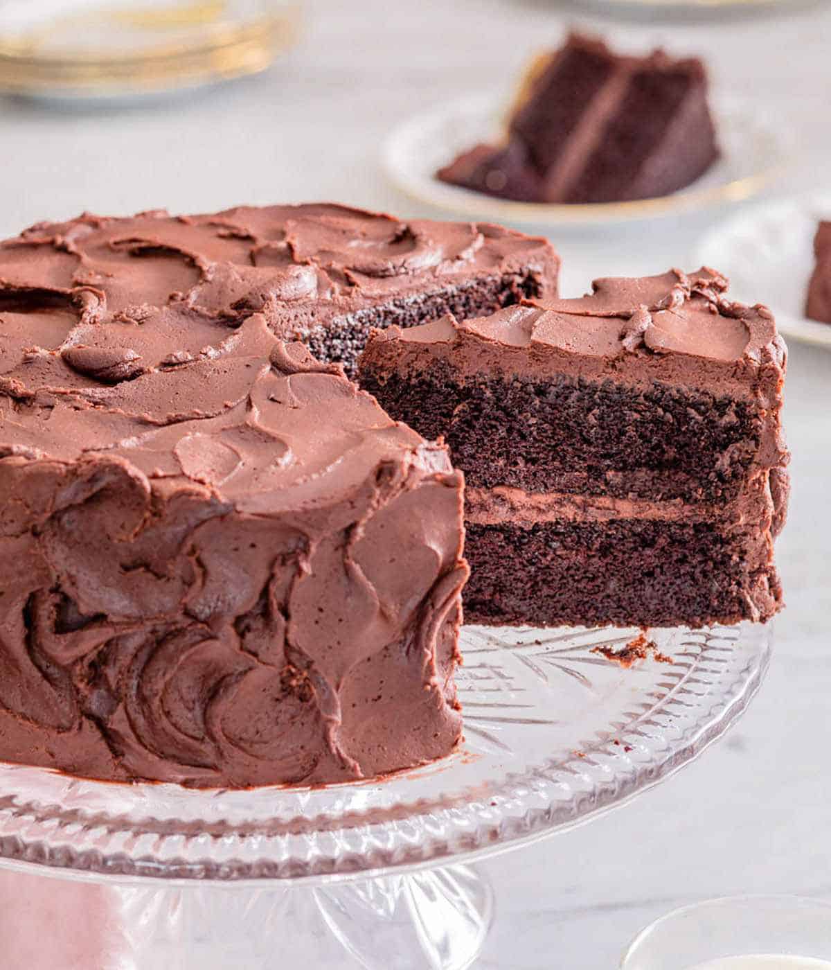 Devil's food cake on a cake stand with a slice cut and pulled out.