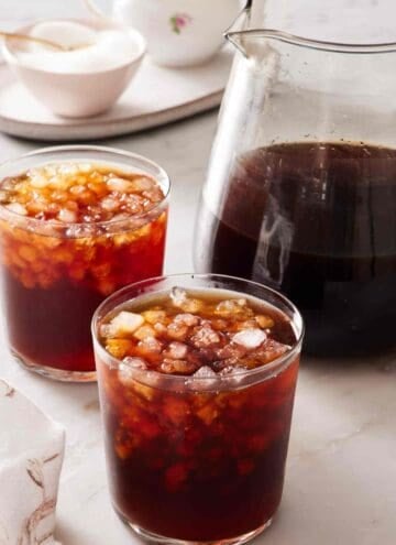 Two glasses of cold brew next to a pitcher with more coffee.