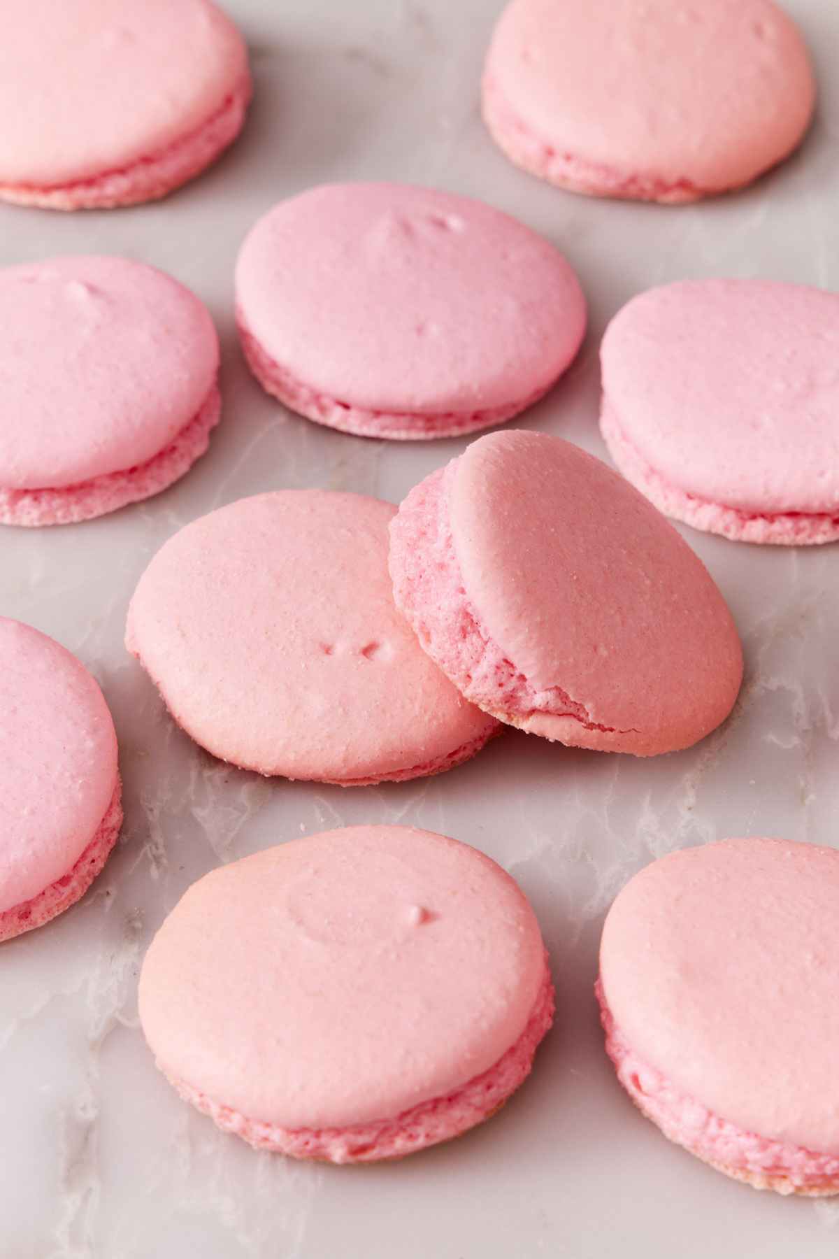 Several macaron shells baked with a slanted top on a counter.