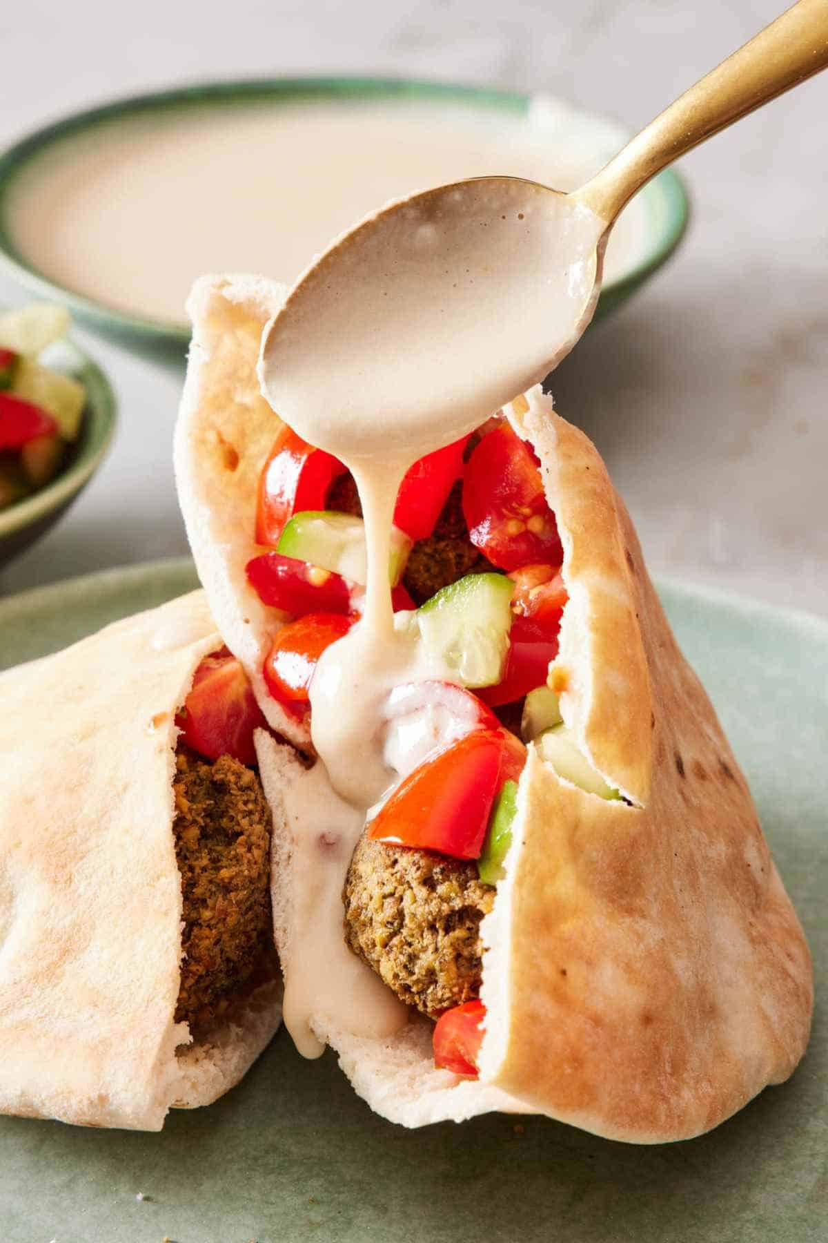 Tahini sauce drizzled over a falafel pita.