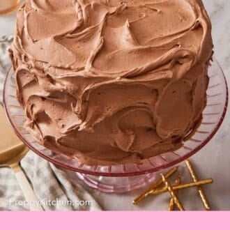 Pinterest graphic showing a frosted yellow cake on a cake stand with candles next to it.