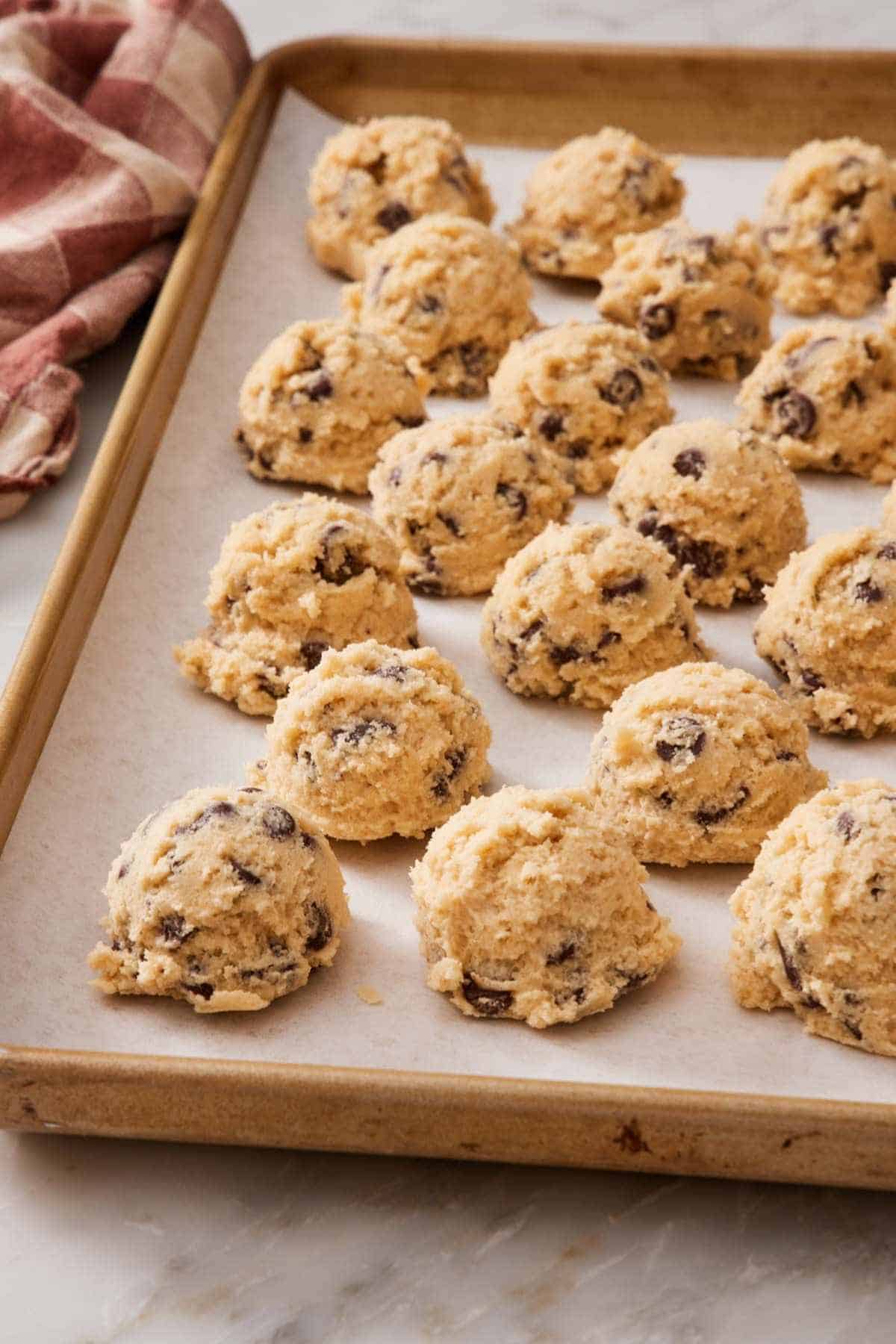 Scooped cookie dough balls on a lined baking sheet.