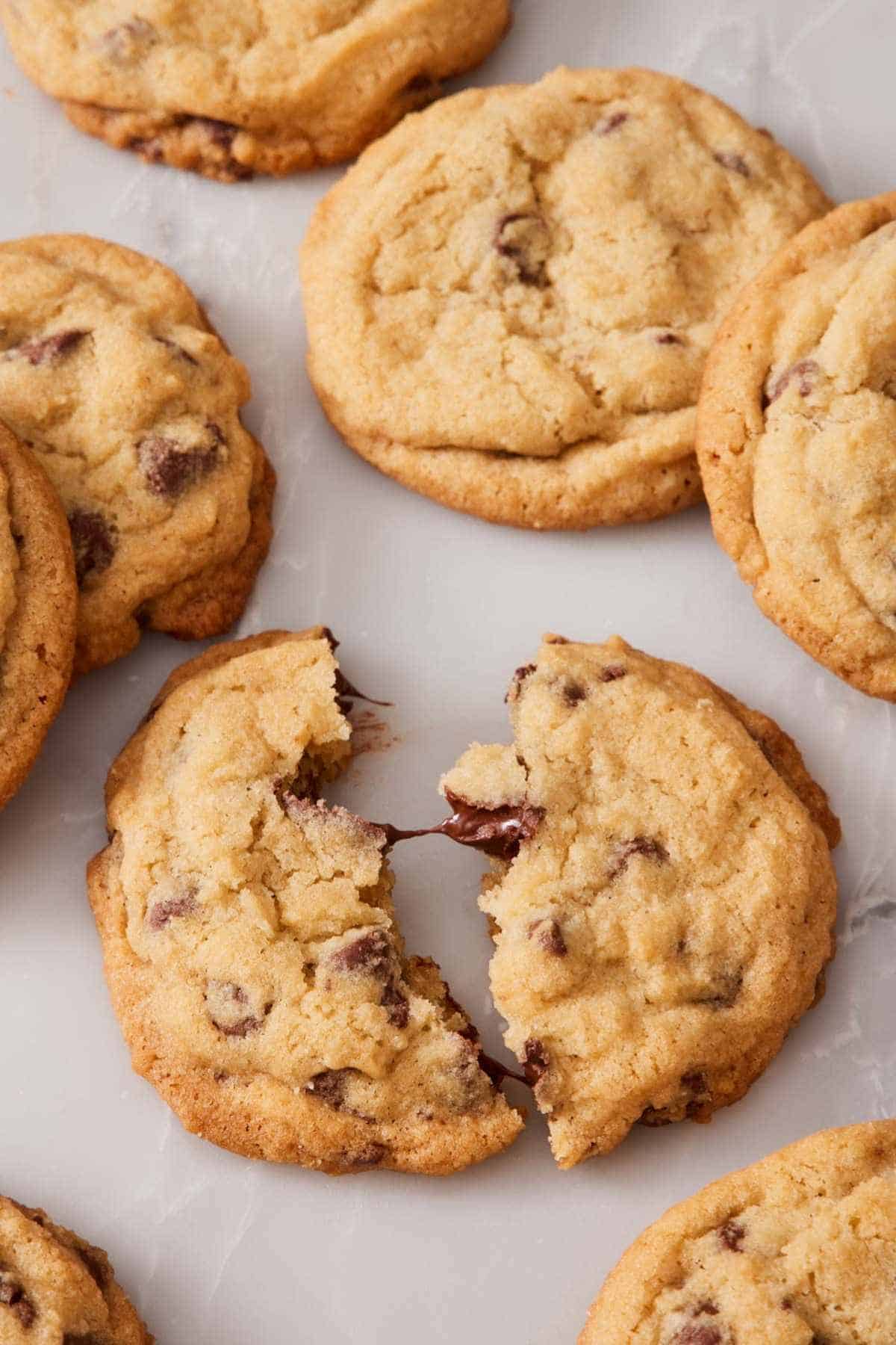Overhead shot of chocolate chip cookies, one torn in half.