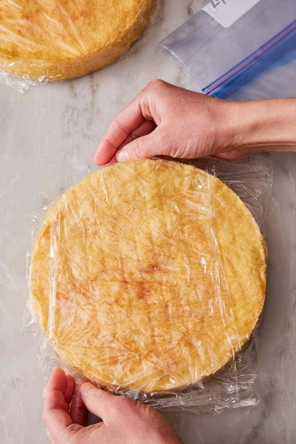 A cake layer wrapped tightly with plastic wrap to show how to freeze cakes.
