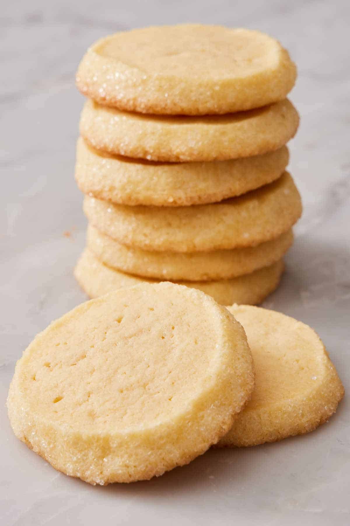 A stack of butter cookies with two in front.