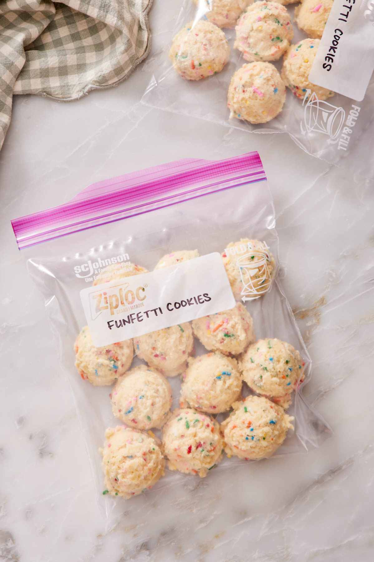 An overhead shot of funfetti cookie dough balls in a freezer bag with another bag of dough balls mostly out of frame.