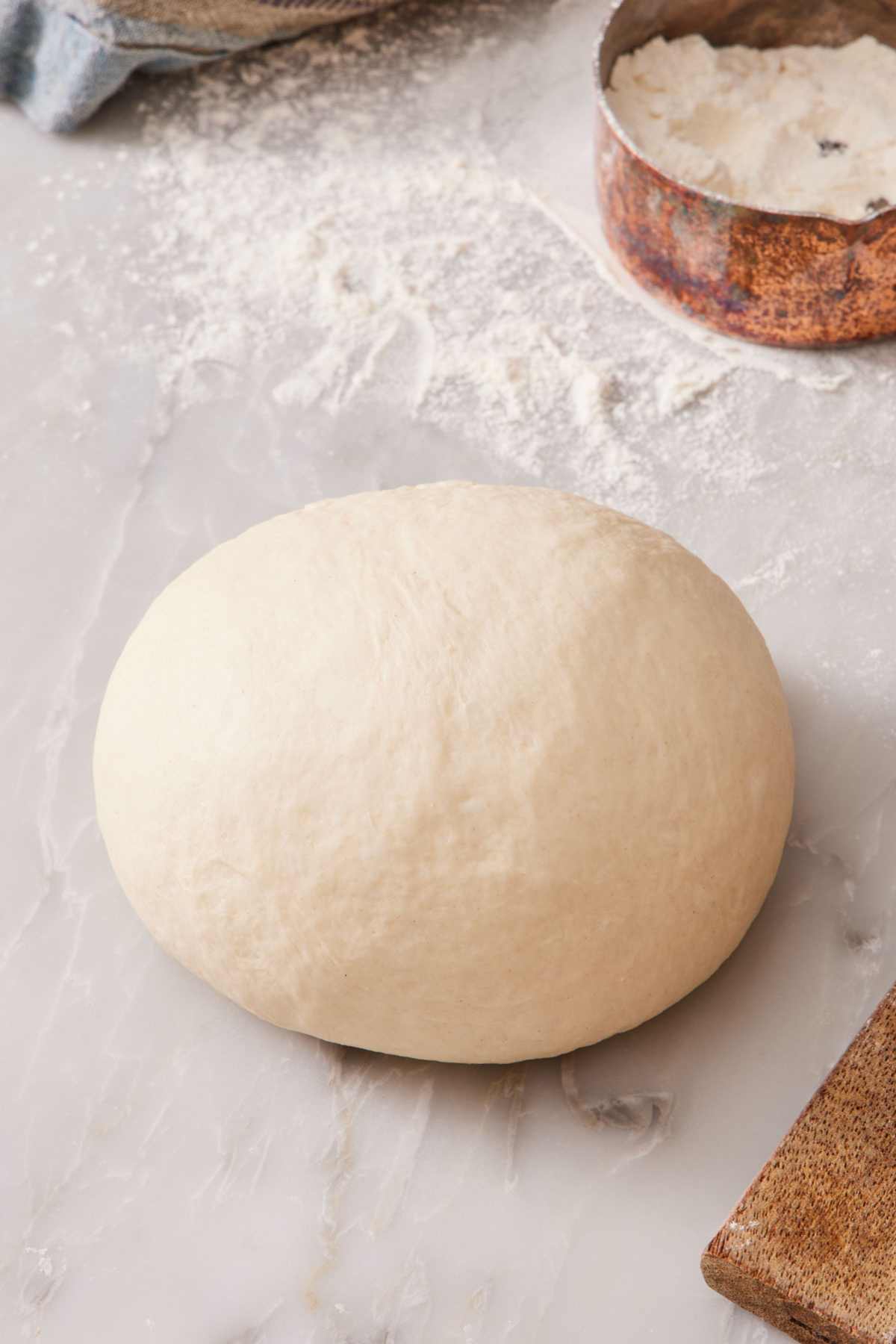 A smooth ball of kneaded dough on a white countertop.