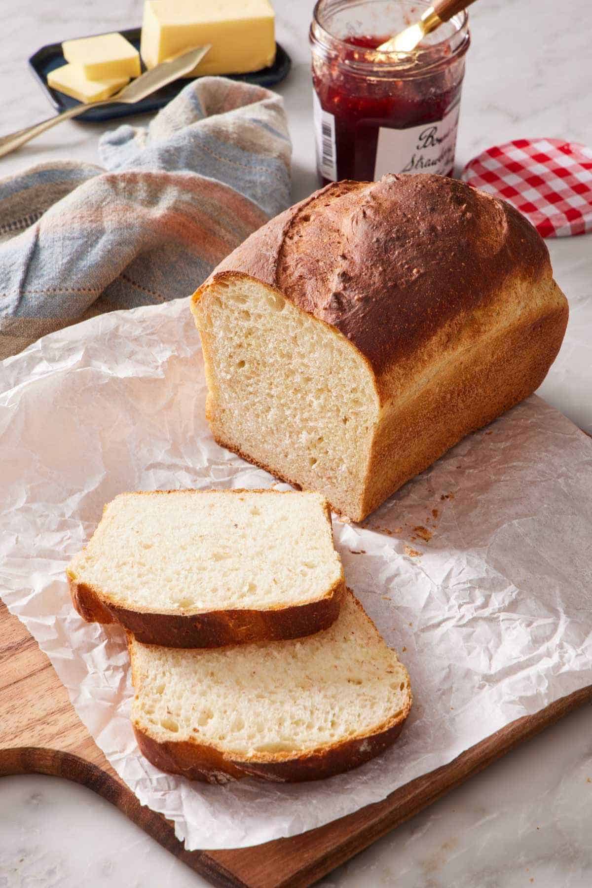 A loaf of homemade bread with two slices cut out and laying down next to it.